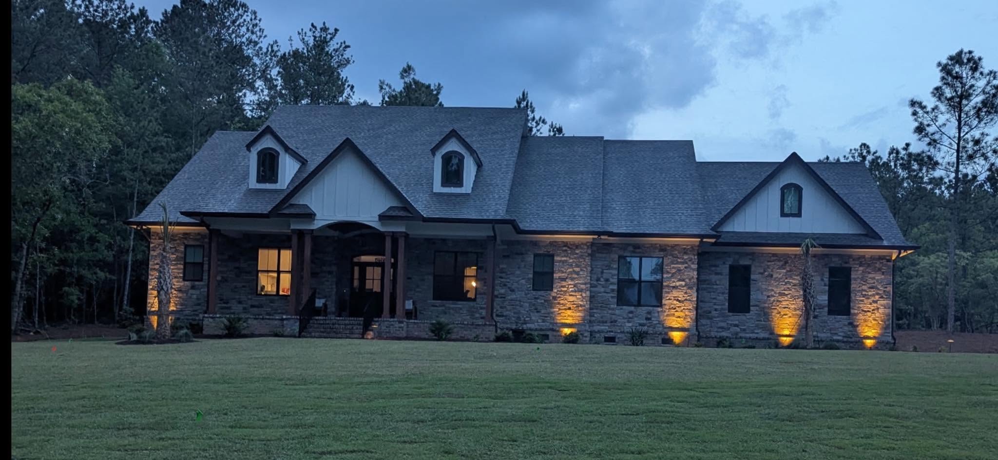 Completed natural-stone residence with warm exterior lighting at dusk