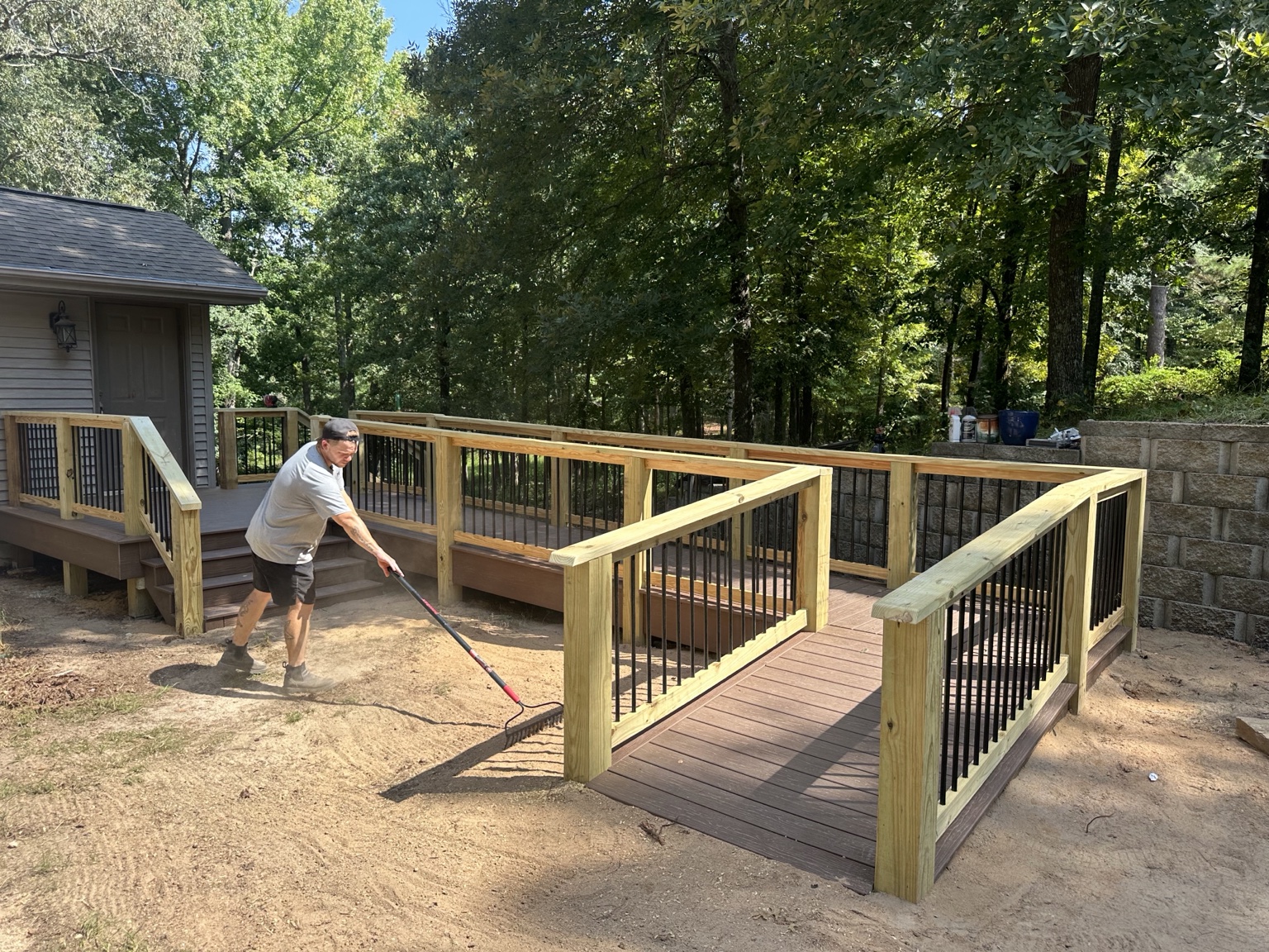Custom composite deck and accessible ramp with pressure-treated rails and black metal balusters during final site work