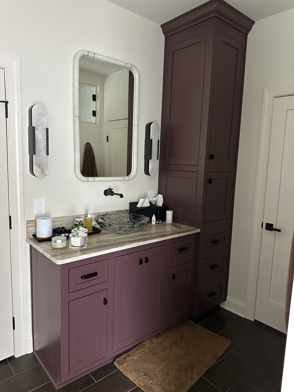 Custom plum bathroom cabinetry with inset doors, integrated tall storage, stone counter, vessel sink, and black fixtures