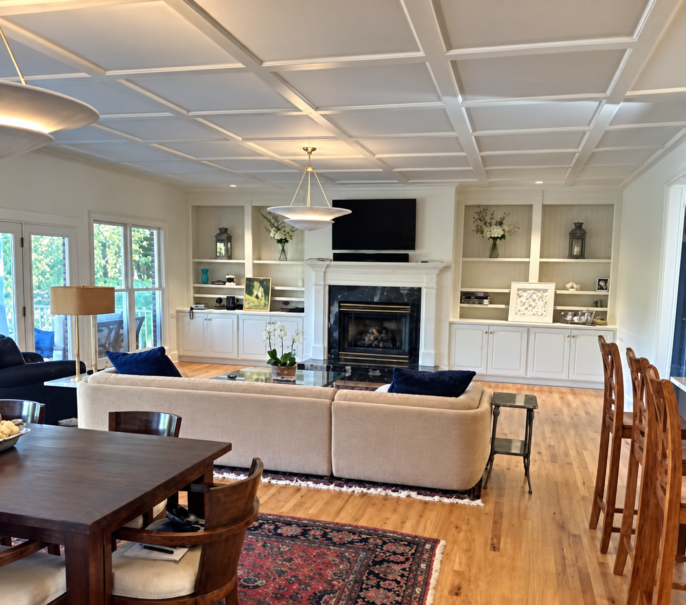 Completed open living and dining room with a full coffered ceiling, fireplace, and built-in cabinetry